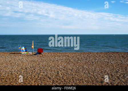 Se prélasser sur la plage colorés set stony plage face à une mer calme, Hythe, dans le Kent Banque D'Images