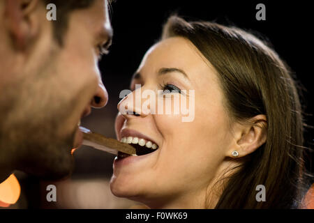 Jeune couple de manger ensemble un morceau de chocolat - dans la rue la nuit Banque D'Images