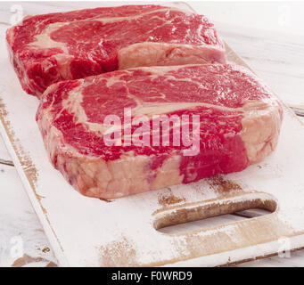 Ribeye Steak frais crus sur une planche à découper en bois. Banque D'Images