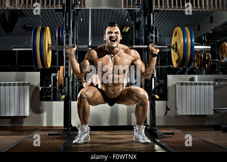 Bodybuilder , très intense guy exécuter l'exercice accroupi avec le poids, dans la salle de sport Banque D'Images