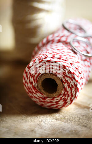 Bobine de ficelle rouge et blanche avec des ciseaux sur fond de bois Banque D'Images