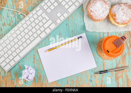 Designer graphique de l'espace de table rustique avec clavier de l'ordinateur, dessin vide des feuilles de papier, crayons, tasse de café et beignes Banque D'Images