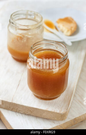 Sauce au caramel dans un bocal en verre sur un fond de bois Banque D'Images