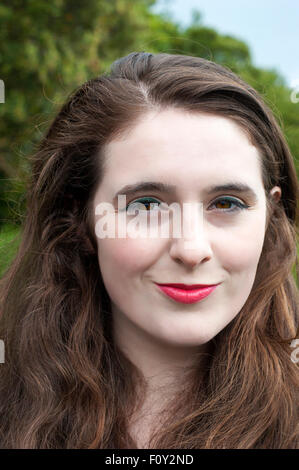 Portrait d'une jeune femme avec des yeux noisette, et des cheveux bruns bouclés. Banque D'Images