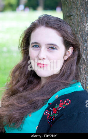 Portrait d'une jeune femme avec des yeux noisette, et des cheveux bruns bouclés. Banque D'Images