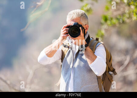 Homme d'âge moyen de prendre des photos dans la vallée de montagne avec votre appareil photo reflex numérique Banque D'Images