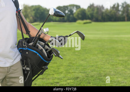 Photo en gros plan du sac de golf par un golfeur. Dans l'homme blanc T-shirt et pantalon crème en prenant un pilote pour lancer son jeu sur rendez-vous Banque D'Images