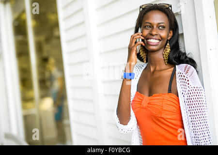 Beau noir femme parlant au téléphone et souriant pendant un jour d'été Banque D'Images