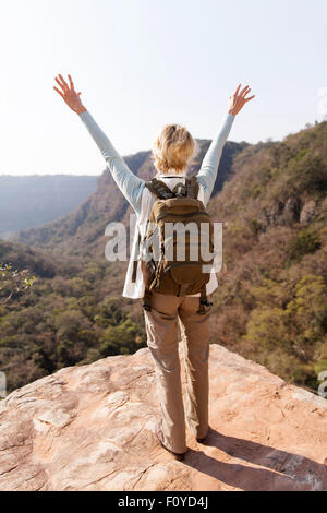 Vue arrière de female hiker bras ouverts sur la falaise de montagne Banque D'Images