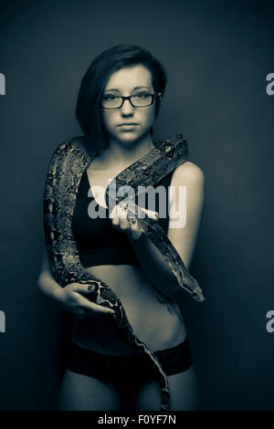 Une jeune femme fille femme portant des lunettes qui posent avec serpent , UK (ne souffre pas d'ophiophobia - la peur des serpents) Banque D'Images