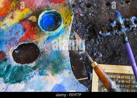 La palette de l'artiste, un couteau et une brosse et d'un diluant sur le chevalet à un atelier d'artiste Banque D'Images