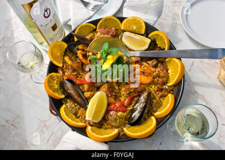 PAELLA ALFRESCO RUSTIQUE espagnol fruits de mer en plein air cuisiné dans un Paellera sur une table ensoleillée en plein air restaurant, verres de Lanzarote Vega de Yuco vin Espagne Banque D'Images