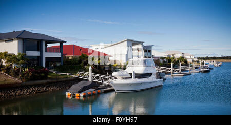 Beau yacht blanc amarré en face d'une maison avec un jardin sur une journée ensoleillée Banque D'Images