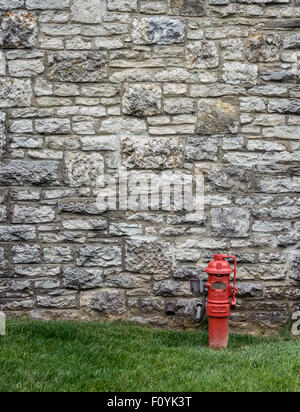 Une bouche d'incendie rouge contraste contre un mur de pierre à une distillerie le long du sentier de Bourbon Banque D'Images