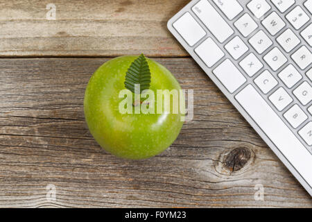 Vue de dessus de la pomme verte, selective focus sur le dessus des feuilles, avec vue partielle sur le clavier de l'ordinateur en bois rustique. Banque D'Images