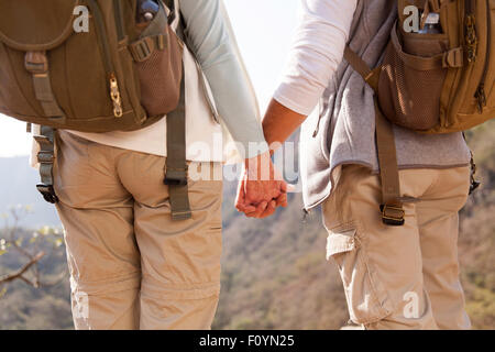 Vue arrière du couple holding hands randonnées en montagne Banque D'Images