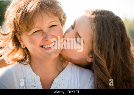 Close up of teenage girl hugging et embrassant sa mère h piscine dans la nature aux beaux jours Banque D'Images