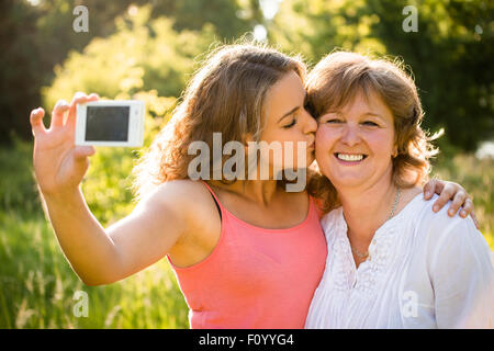 Sa fille adulte embrasser la haute mère tout en prenant des photos avec un téléphone mobile selfies Banque D'Images