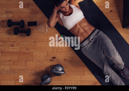 Sporty young woman lying on exercise mat faire des sit-ups. Vue de dessus de la femme faisant des craquements abs. Banque D'Images