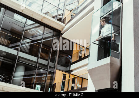 Businessman taking ascenseur en verre moderne à l''étage supérieur Banque D'Images