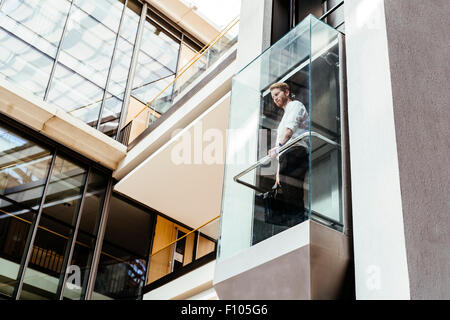 Businessman taking ascenseur en verre moderne à l''étage supérieur Banque D'Images