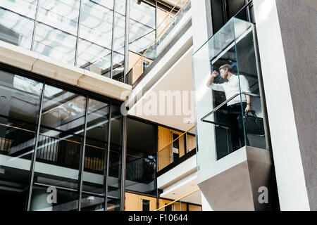 Businessman taking ascenseur en verre moderne à l''étage supérieur Banque D'Images