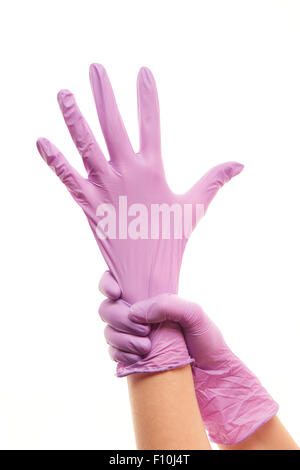 Close up of woman's hands mettre des gants chirurgicaux stériles violettes sur fond blanc contre Banque D'Images