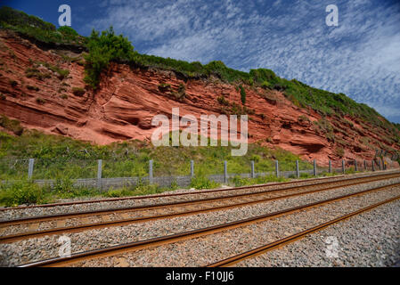 Falaises de grès rouge à côté de la ligne de chemin de fer côtière. Banque D'Images