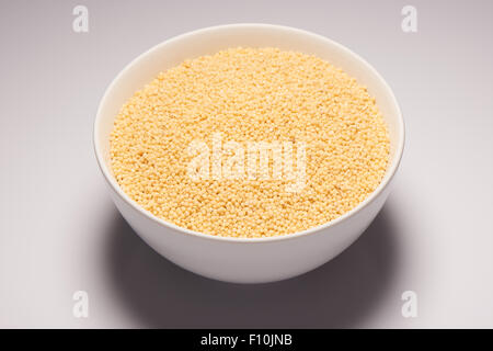 Millet biologiques crus croupe dans Bol en céramique blanche sur fond blanc Banque D'Images