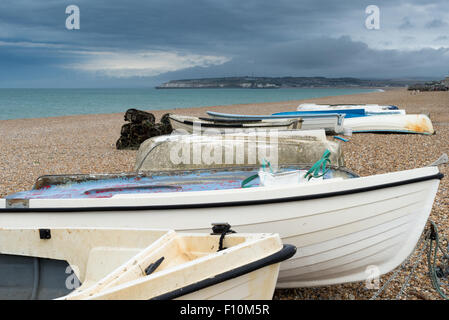 Les petits bateaux de pêche sur une plage de galets sous un ciel d'orage Banque D'Images