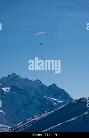 Un parapente vole très haut dans les montagnes couvertes de neige au-dessus des montagnes à Blatten/Belalp, Suisse (canton du Valais). Banque D'Images