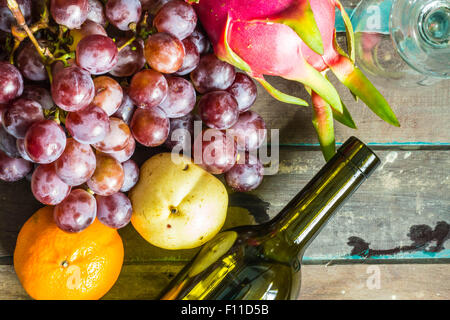 Beaucoup de fruits et des bouteilles de vin allongé sur un sol en bois Banque D'Images