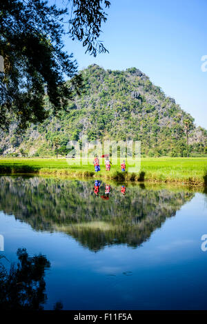 Asian family walking past lake in rural field Banque D'Images