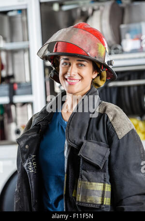 Heureux pompier femelle debout contre les pompiers Banque D'Images