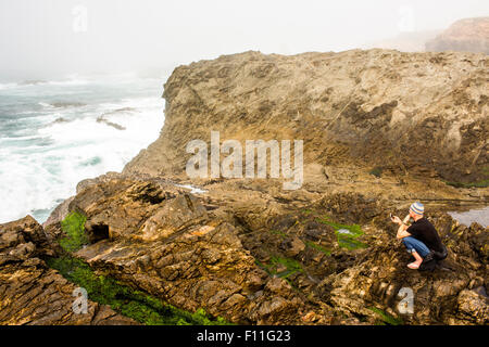 Caucasian hiker assis sur des falaises sur l'océan, Mendocino, California, United States Banque D'Images