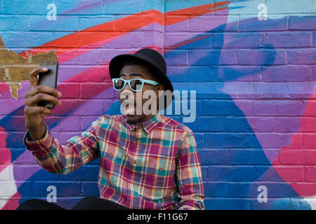 Homme noir en tenant près de selfies colorful wall Banque D'Images