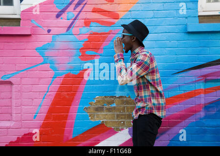 Homme noir à lunettes crier près de colorful wall Banque D'Images