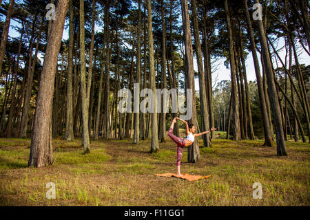 Hispanic woman practicing yoga in forest Banque D'Images