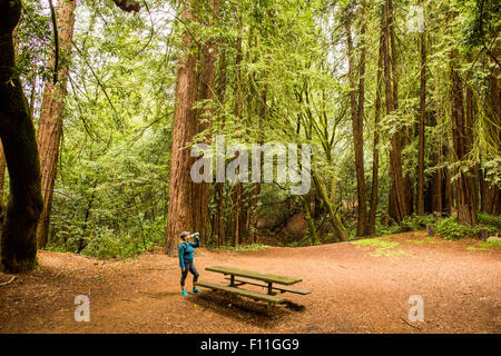 Caucasian woman drinking from bottle dans le dégagement de forêt Banque D'Images