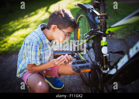 Mixed Race boy huilage chaîne de bicyclette dans la cour Banque D'Images