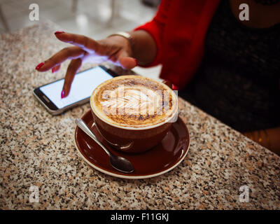 Mixed Race woman with coffee in cafe Banque D'Images