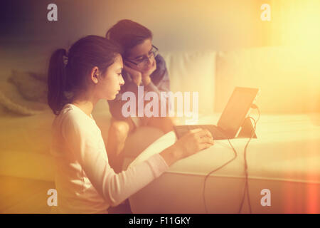 Mixed Race children using laptop on sofa Banque D'Images