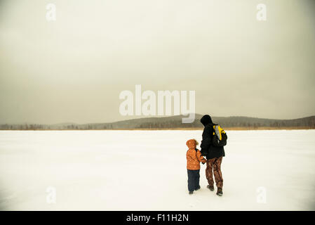 Caucasian father and son walking in snowy field à distance Banque D'Images