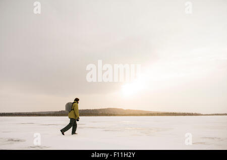 Caucasian hiker walking in snowy field à distance Banque D'Images