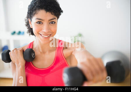 Mixed Race woman lifting weights in gym Banque D'Images