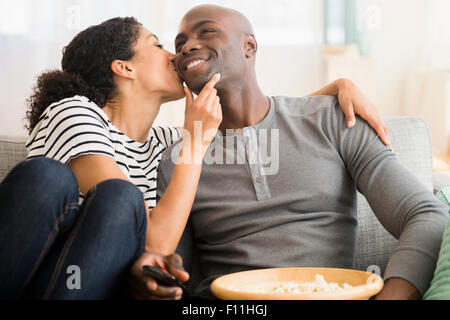 Smiling couple watching television on sofa Banque D'Images