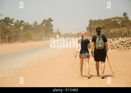 Caucasian couple walking on dirt road in remote field Banque D'Images