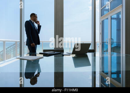 Hispanic businessman talking on cell phone in conference room Banque D'Images