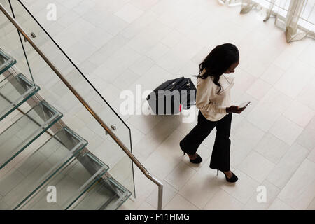 High angle view of businesswoman rolling luggage in hotel lobby Banque D'Images