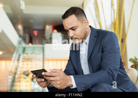 Hispanic businessman using digital tablet in hotel lobby Banque D'Images